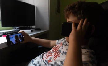 Un niño usa el teléfono móvil y una tablet.