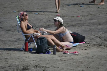 Dos mujeres descansan al sol en una playa de Montevideo.