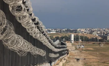 Desplazados palestinos caminan cerca del muro que construye Egipto para contener a los habitantes de la Franja de Gaza que quieren cruzar la frontera. Las obras se aceleran ante la inminente ocupación de la ciudad de Rafa por parte de las tropas israelíes.