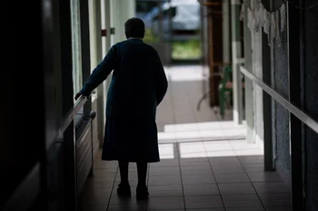 Anciana camina por el pasillo de un geriátrico