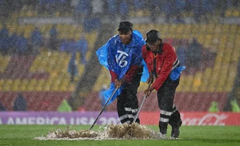 Con lampazos intentan retirar el agua de la cancha, mientras sigue lloviendo en el Campín de Bogotá en Millonarios vs Peñarol por la Copa Sudamericana