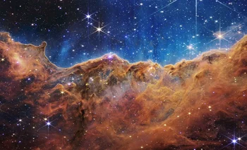 Esta imagen publicada por la NASA el 12 de julio de 2022 desde el Telescopio espacial James Webb (JWST) muestra un paisaje de "montañas" y "valles" salpicado de estrellas brillantes que en realidad es el borde de una región cercana, joven y de formación estelar. llamado NGC 3324 en la Nebulosa Carina. Capturada en luz infrarroja por el JWST, esta imagen revela por primera vez áreas de nacimiento estelar previamente invisibles.