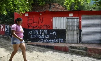 Una mujer pasa frente a una pintada que propagandiza la radio clandestina del ELN. 