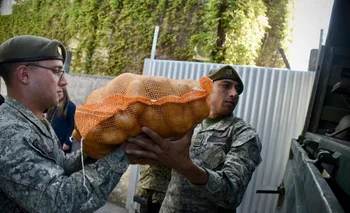 Dos efectivos cargan una bolsa de papas a un camión del Ejército