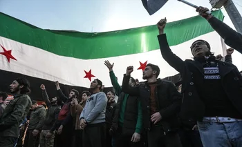 Manifestantes levantan banderas y pancartas de la oposición siria mientras protestan contra un posible acercamiento entre Ankara y el régimen sirio